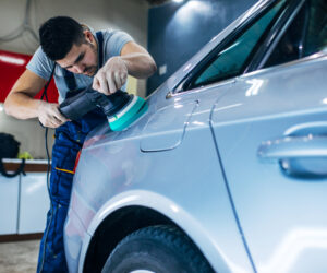 Portrait of a young serviceman polishing a car.